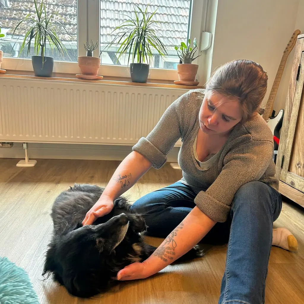 Yvonne Krüger untersucht einen kleinen schwarzen Hund auf dem Wohnzimmerboden